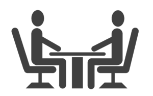 two people speaking while seated at a table